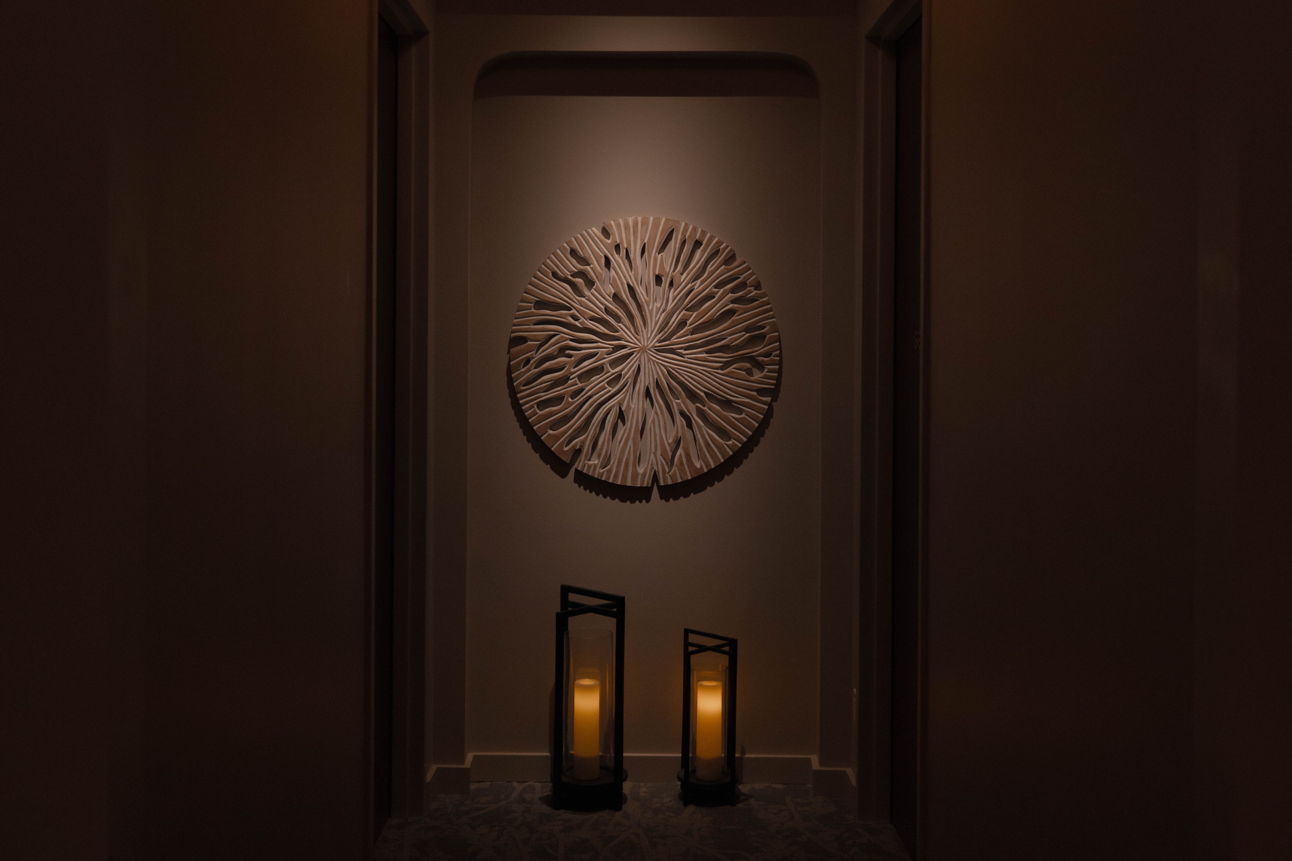 Tranquil hallway at Exhale Spa featuring a decorative wall art piece and illuminated lanterns, creating a serene atmosphere for wellness and relaxation.