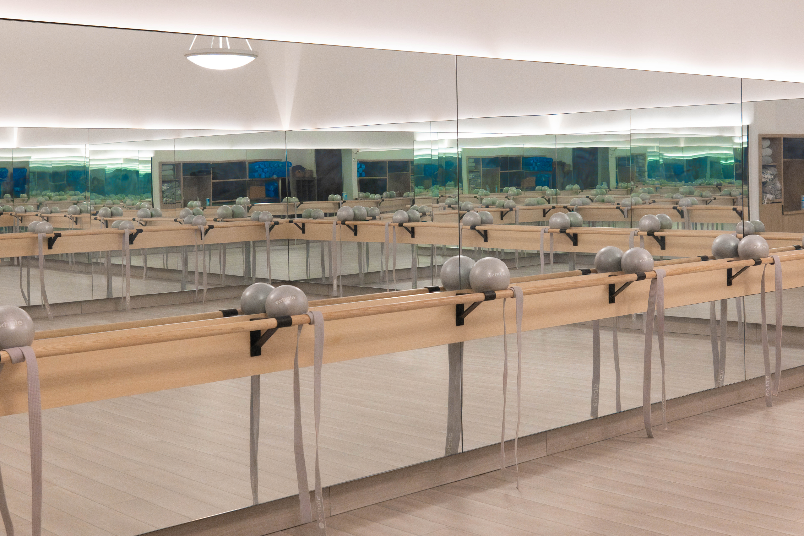 Fitness studio with mirrored walls, wooden barre, and exercise balls, illustrating wellness and fitness offerings at Exhale Spa near Central Park.