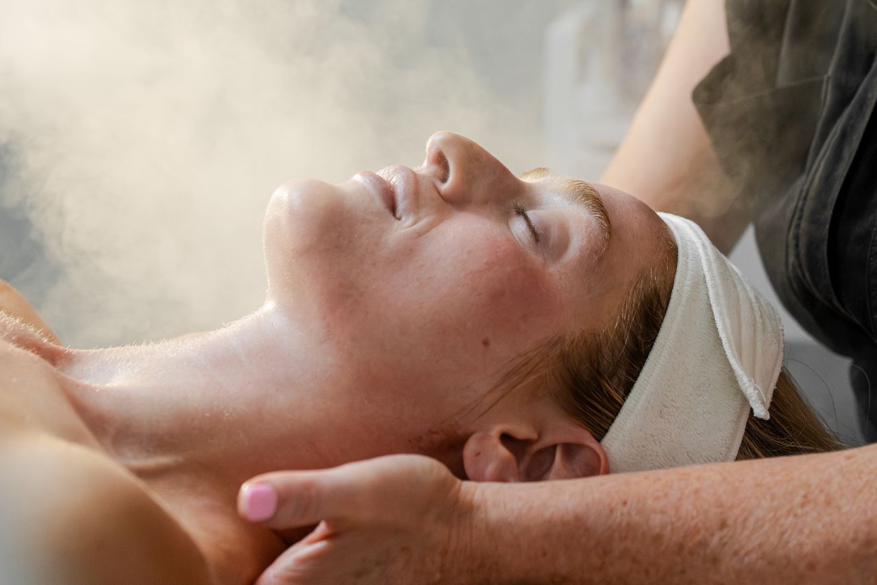 Woman receiving facial treatment with steam, experiencing relaxation at Exhale Spa, Boston, highlighting wellness and skincare services.