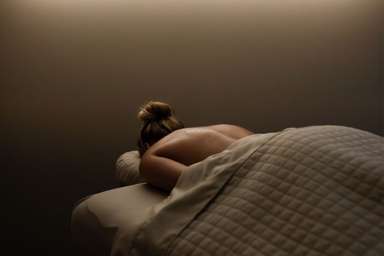 Woman receiving a massage at a luxury spa, emphasizing relaxation and wellness, with soft lighting and a serene atmosphere, reflecting Exhale Spa's focus on rejuvenating therapies.