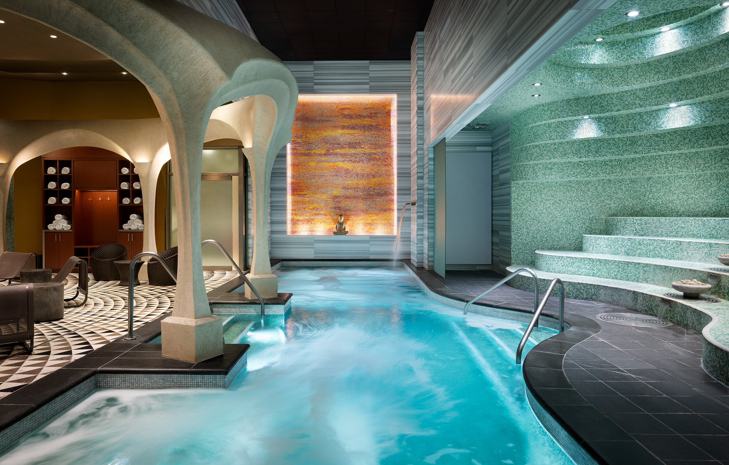 Luxurious spa bathhouse interior at Exhale Spa in Atlantic City, featuring heated pools, mosaic tiles, and serene ambiance with decorative elements and seating areas.