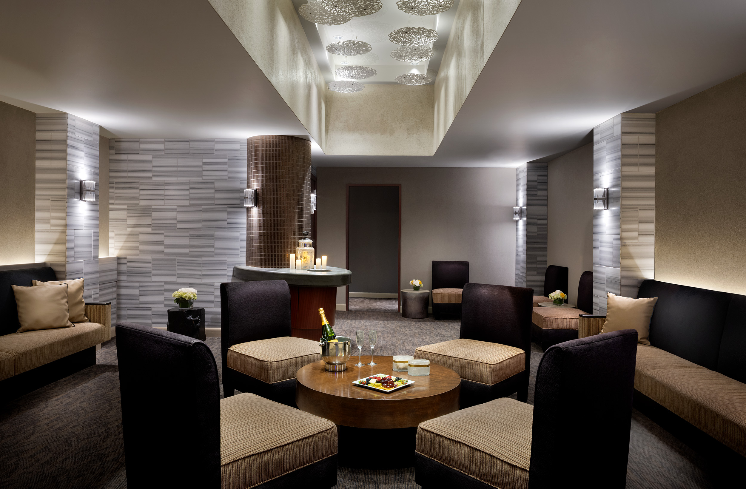 Luxurious spa waiting room at Exhale Spa in Atlantic City, featuring elegant seating, a round table with refreshments, soft lighting, and a calming atmosphere for relaxation.
