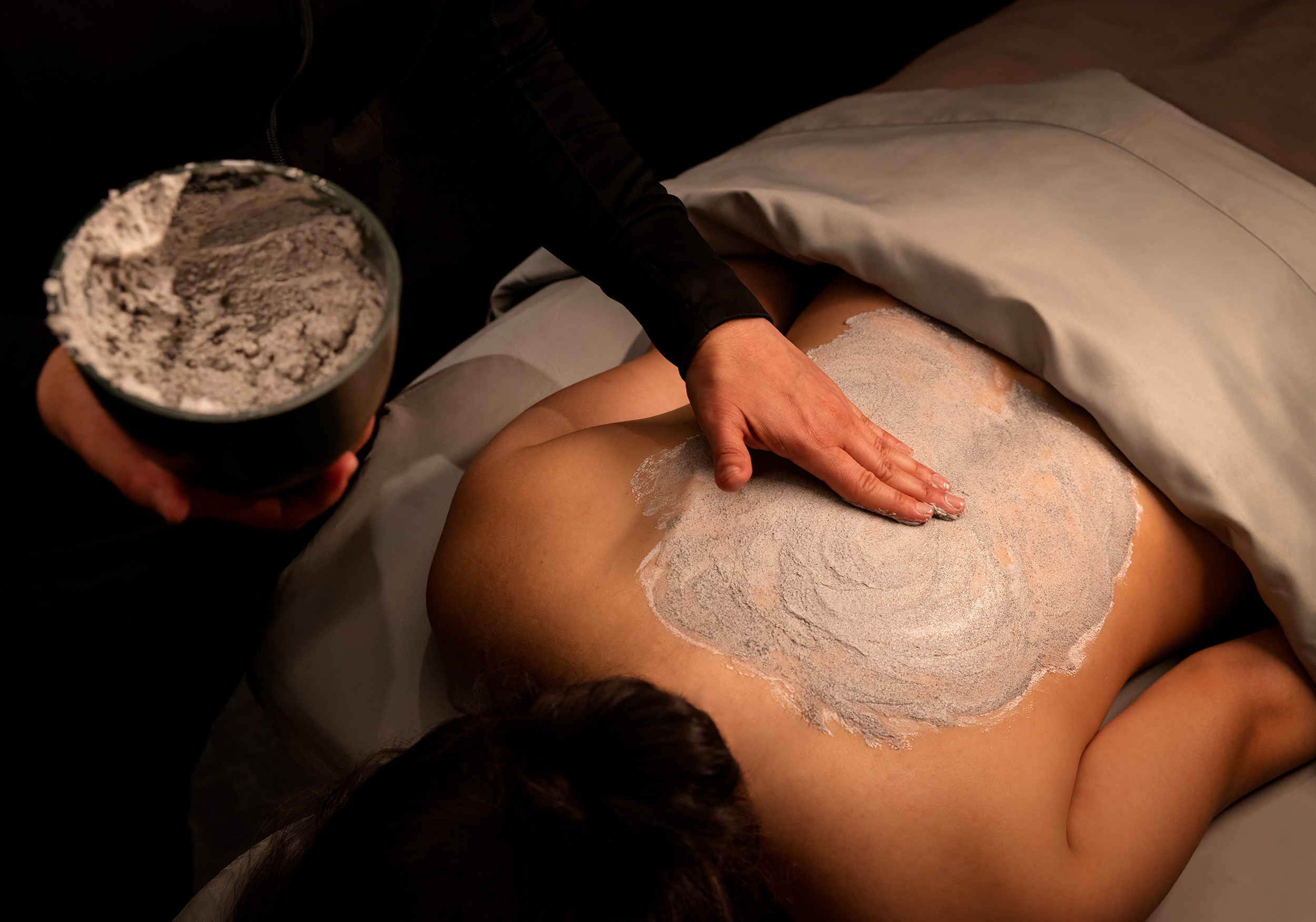 Spa therapist applying a soothing body treatment on a client's back in a tranquil wellness environment at Exhale Spa, Atlantic City.