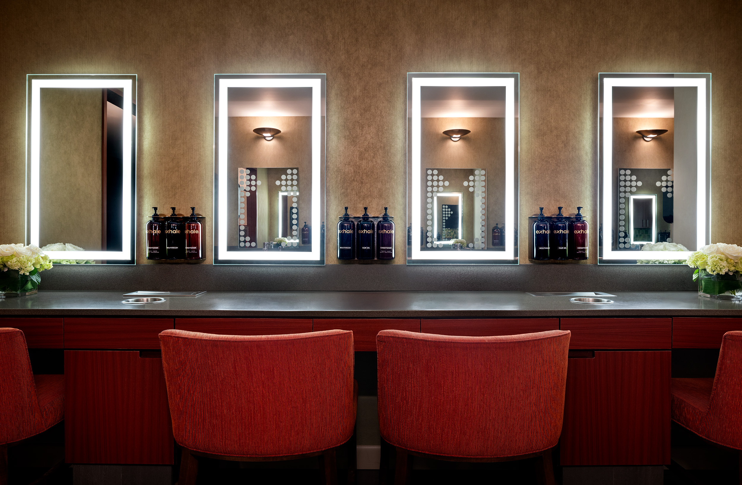 Luxurious spa locker room with illuminated mirrors, modern design, and Exhale branded skincare products on display, promoting relaxation and wellness at Exhale Spa in Atlantic City.